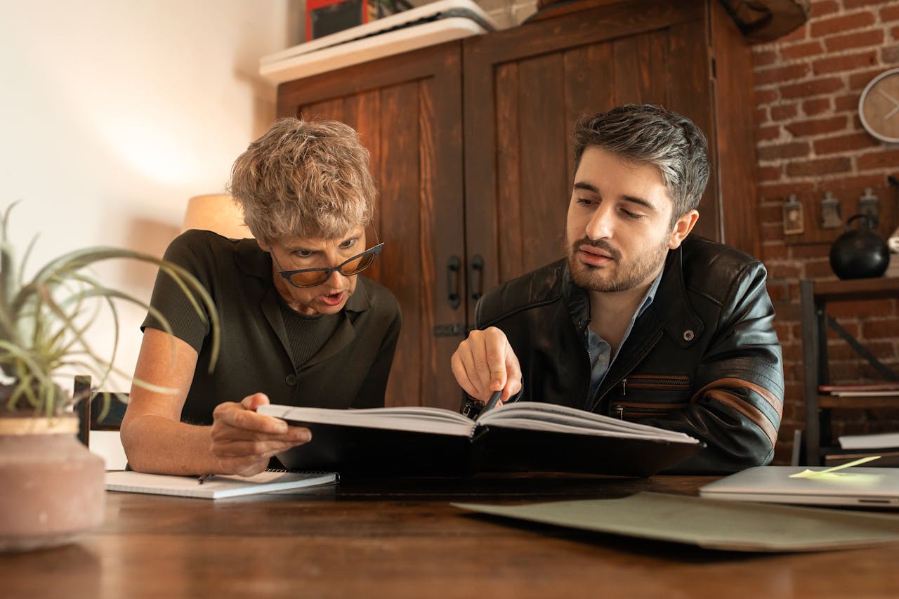 An elderly woman and a man study together in a cozy indoor environment.