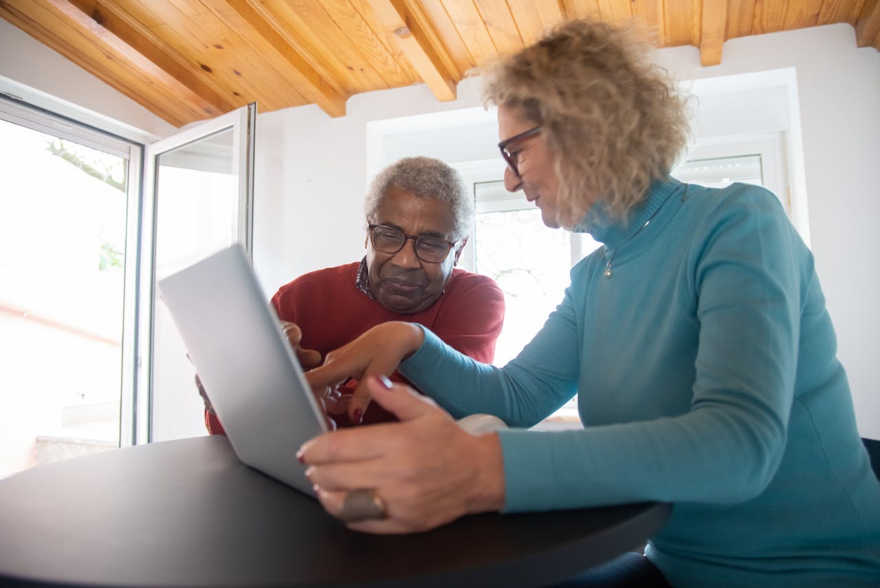 An elderly couple using a laptop for online shopping while sitting indoors in Portugal.